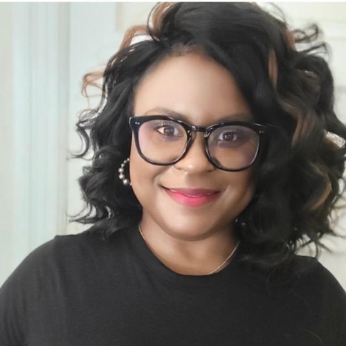 Clarise, a woman with wavy black hair and subtle brown highlights, is smiling. She wears black-rimmed glasses, pearl earrings, a black top, and vibrant red lipstick. The light-colored background is softly blurred.